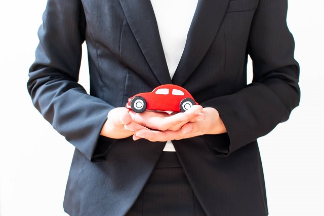 車のミニチュアを持つ人物
